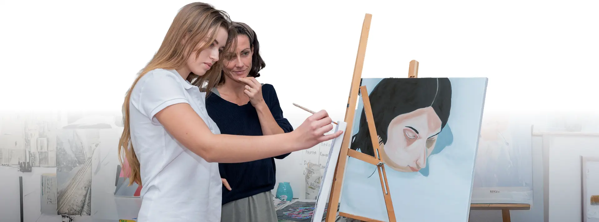 Surval Montreux student painting at an easel with guidance from a teacher in the art studio.