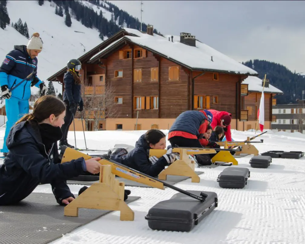 Participants taking part in a biathlon shooting session on snow